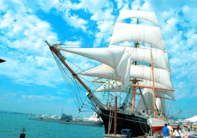 A 19th century cargo ship called the Star of India with its many sails unfurled with a complex network of ropes and pulleys against a bright blue sky in the San Diego Bay