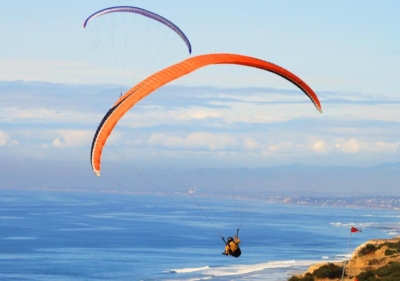 Two hang gliders soaring high above the Pacific Ocean in Torrey Pines, San Diego
