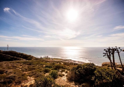 Photo of beach next to cliffs with sun glare