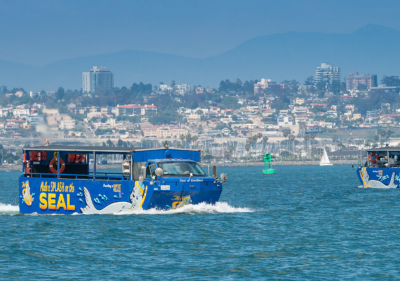 two seal tour vehicles cruise san diego bay with skyline of san diego in the background